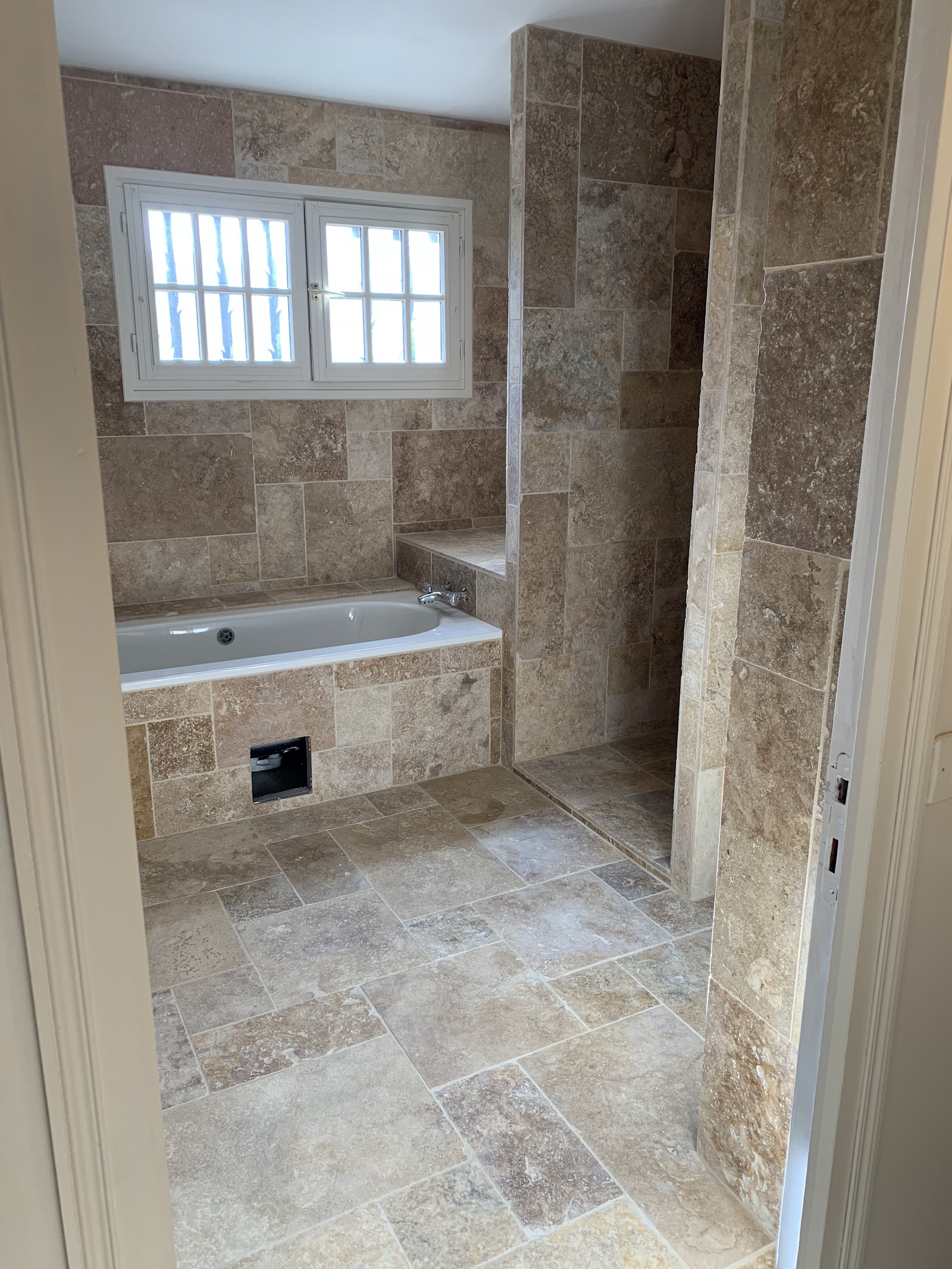 Salle de bain moderne entièrement revêtue de pierre naturelle, réalisation Capelle couverture.