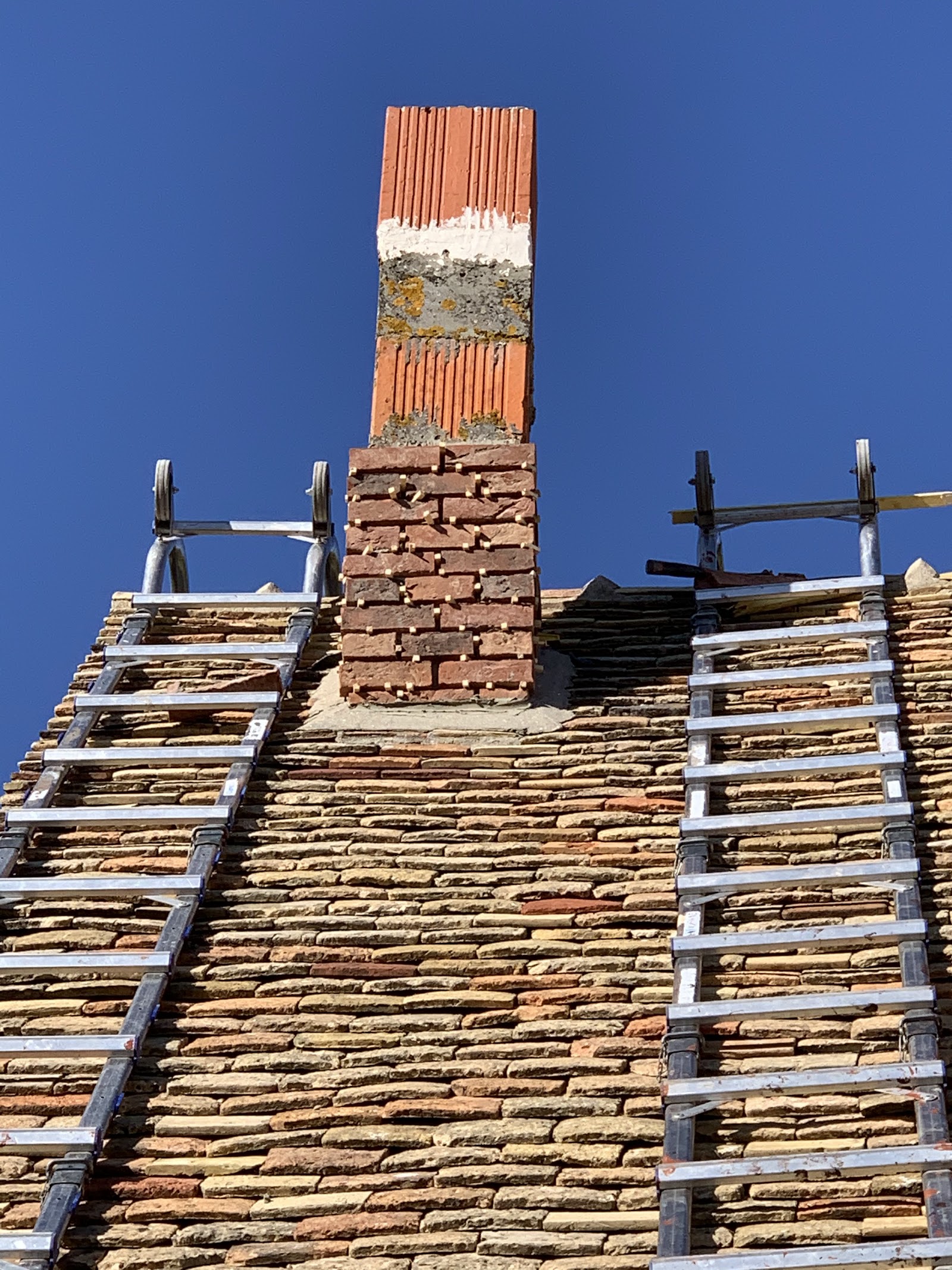 Travaux de maçonnerie sur une souche de cheminée en briques.